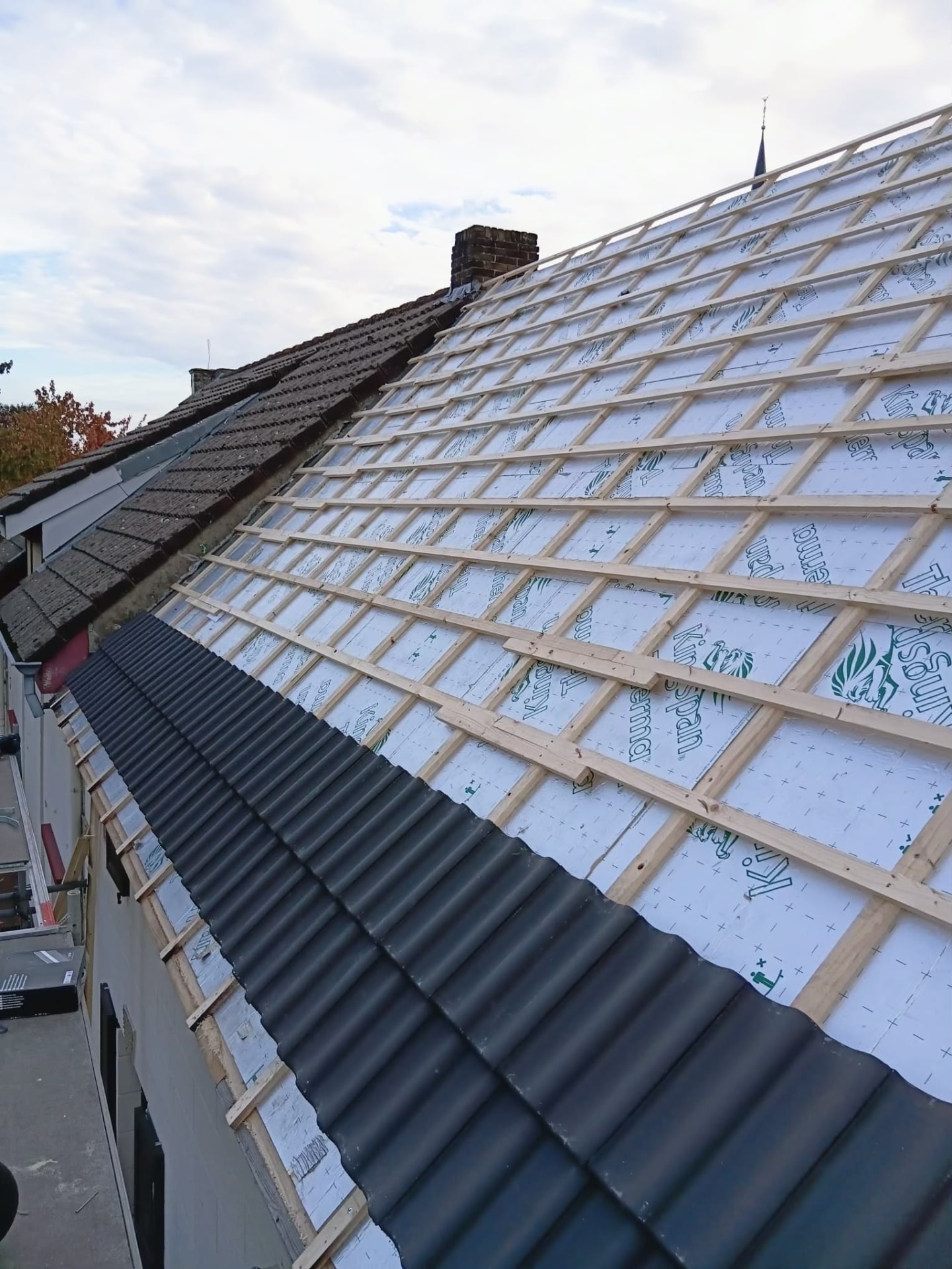 Nieuwe dakpannen op de draaglatten met dampscherm tijdens de renovatie