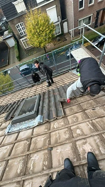 Dakdekker inspecteert dakpannen op een hellend dak